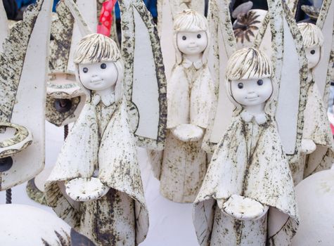 amazing cute white crockery clay ceramic angel sculptures figures looks like alive sold in outdoor marketplace fair.