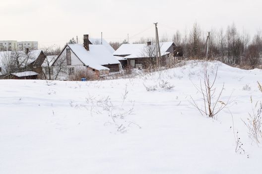 old wooden houses with abundant snowy rooftops on the outskirtss of town in cold winter time