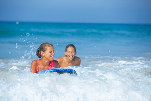 Summer vacation - Two cute girls having fun with surfboard in the ocean