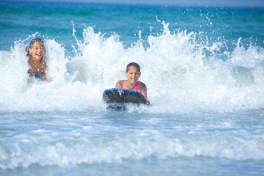 Summer vacation - Two cute girls having fun with surfboard in the ocean