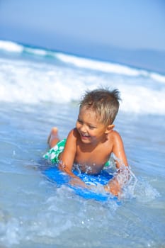 Boy has fun on the surfboard in transparency sea