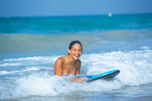 Summer vacation - Happy cute girl having fun with surfboard in the ocean