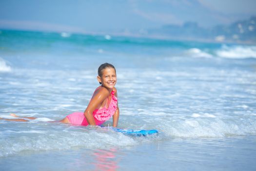 Summer vacation - Happy cute girl having fun with surfboard in the ocean