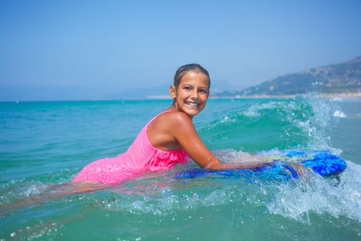 Summer vacation - Happy cute girl having fun with surfboard in the ocean