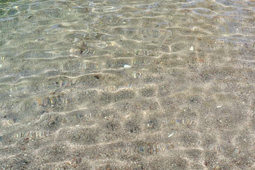 Texture of small pebbles of the sea bottom seen through the water