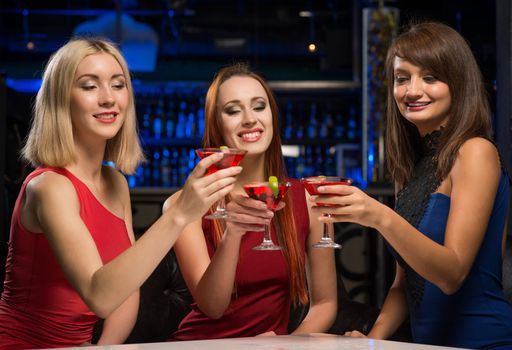 three girls raised their glasses in a nightclub, have fun with friends