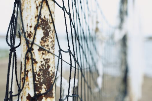 Old net attached to the poles at the beach. Shallow depth of field added for more natural view