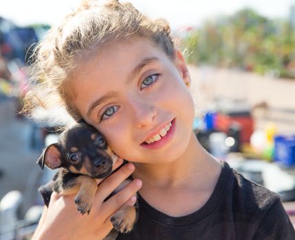 kid girl playing with puppy dog smiling with blue eyes