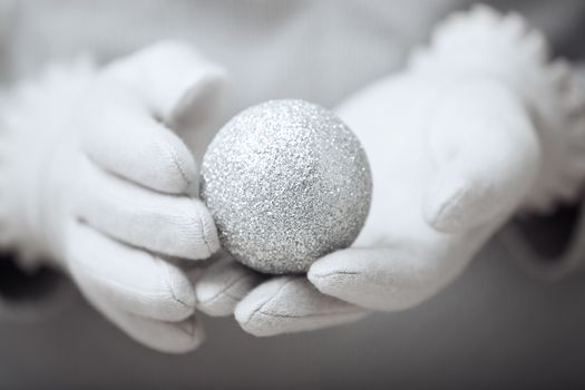 Human hands in mitten holding Christmas ball