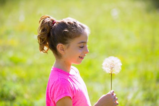 kid girl looking dandelion flower in green meadow outdoor profile view