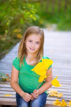 Kid girl in autumn wood deck with yellow leaves relaxed outdoor