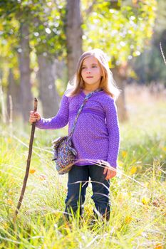 Hiking kid girl with walking stick in autum poplar trees forest