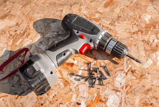 Hand screwdriver and screws on wooden table.