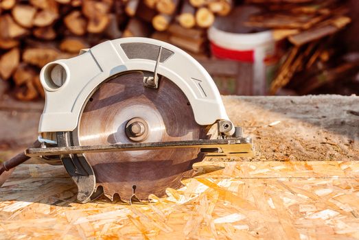 Circular electric saw on the desktop with the wood.