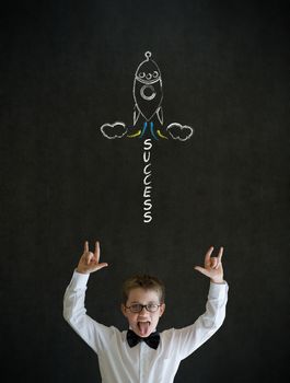 Knowledge rocks boy dressed up as business man with chalk success rocket on blackboard background