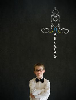 Thinking boy dressed up as business man with chalk success rocket on blackboard background