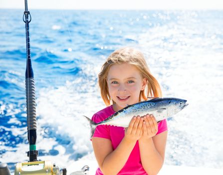 Blond kid girl fishing tuna little tunny happy with trolling catch on boat deck