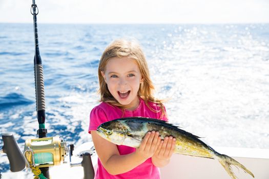 Blond kid girl fishing Dorado Mahi-mahi fish happy with trolling catch on boat deck