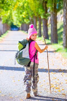 hiking kid girl with walking stick and backpack exploring autumn track and camouflage pants