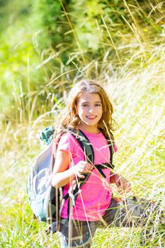 Explorer kid girl walking with backpack between forest grass