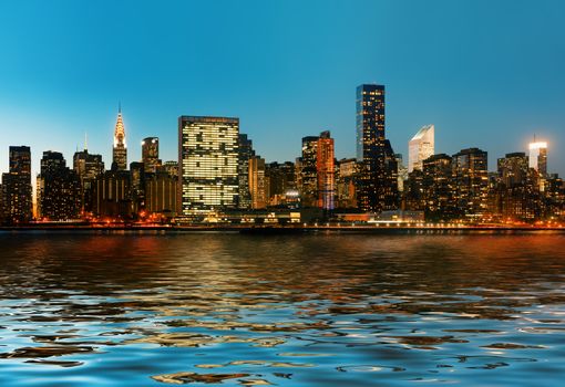 Manhattan. Late evening New York City skyline panorama with lights and reflections.