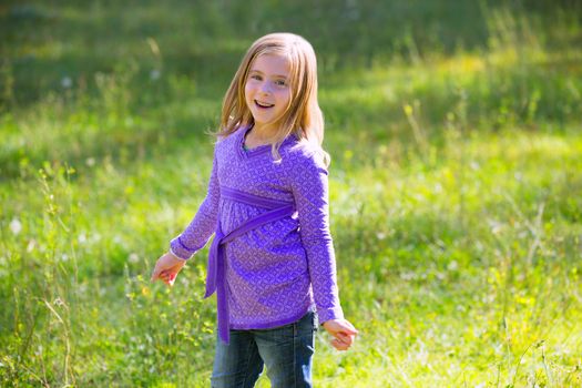 Blond kid girl happy smiling in outdoor green meadow