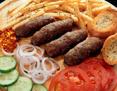 Soutzoukakia - served on dish with french fries, slices of tomato, cucumber and raw onion rings.