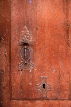 Aged old vintage door knob and keyhole in weathered grunge red wood