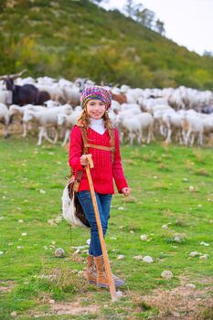 Kid girl shepherdess happy with flock of sheep and wooden stick in Spain