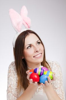 Brunette smiling and holding pile of easter eggs