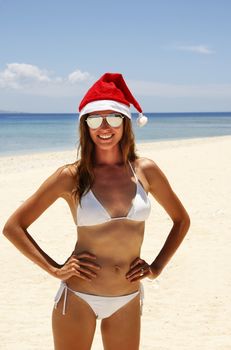 Young woman in santa hat standing on a tropical beach