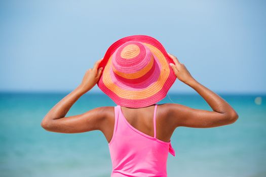 Back view of beautiful girl in pink hat and on background sea