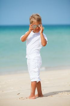 Adorable happy boy in sunglasses on beach vacation