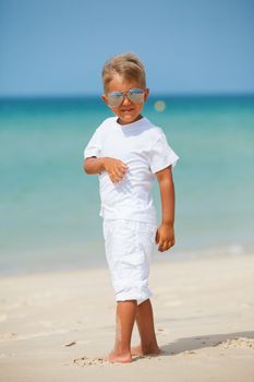 Adorable happy boy in sunglasses on beach vacation