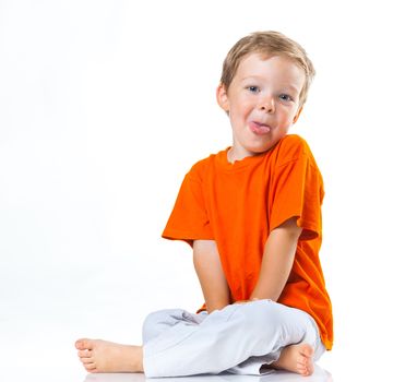 Adorable happy boy sitting on the floor in studio. Isolated of white background.