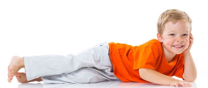 Adorable happy boy lying on the floor in studio. Isolated of white background.