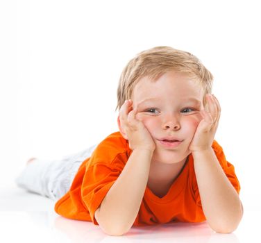 Adorable happy boy lying on the floor in studio. Isolated of white background.