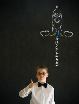 Thumbs up boy dressed up as business man with chalk success rocket on blackboard background