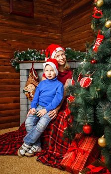 Girl hugs her little brother near Christmas tree