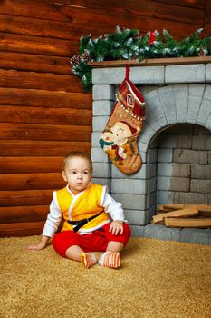 Small boy sitting near Christmas decorations fireplaces