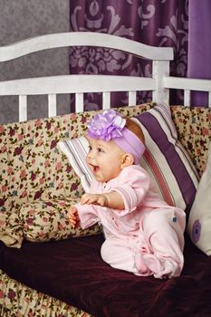 Little girl with bow on her head sitting on couch