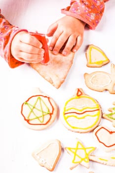 Hands of little girl, who draws on gingerbread cookies