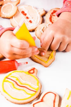 Hands of little girl, who draws on gingerbread cookies