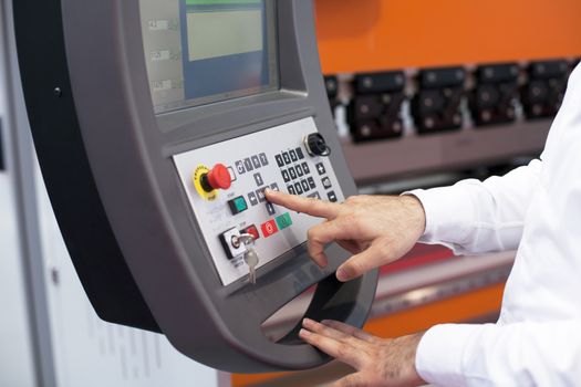 Hand on the control panel of a CNC machine