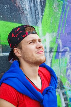 Portrait of happy teens boy sitting near painted wall and having fun