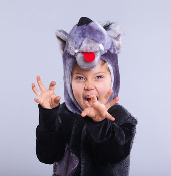 A portrait of a little boy trying a carnival suit of wolf on the grey background