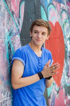 Portrait of happy teens boy having fun near painted wall