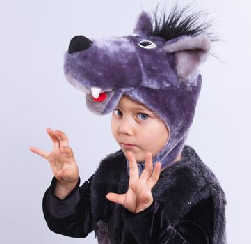 A portrait of a little boy trying a carnival suit of wolf on the grey background