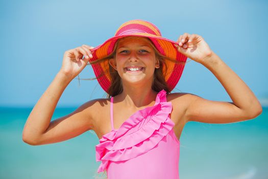 Portrait of beautiful blond girl in pink hat on background sea and blue sky