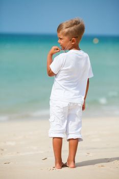 Back view of adorable cute boy on beach vacation